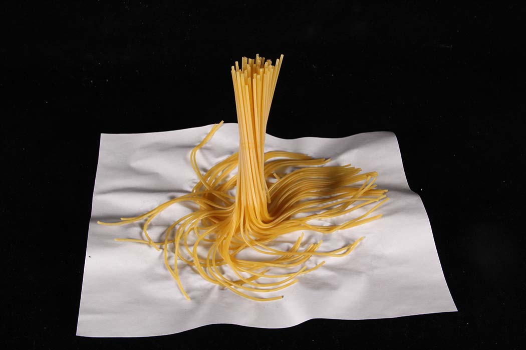 Pasta that is not cooked at the top but cooked on the bottom bound together on a piece of paper